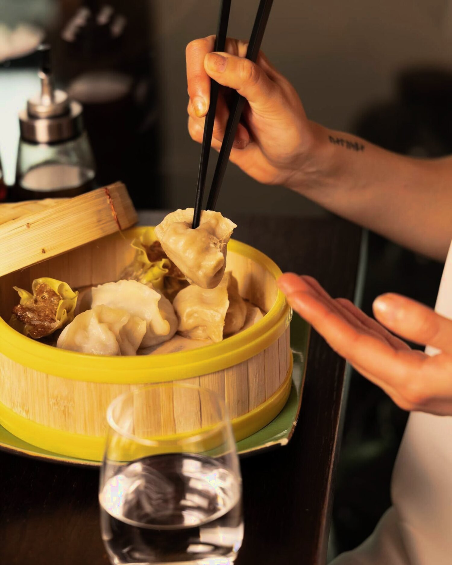 En dampet dumpling løftes med spisepinner fra en bambuskurv